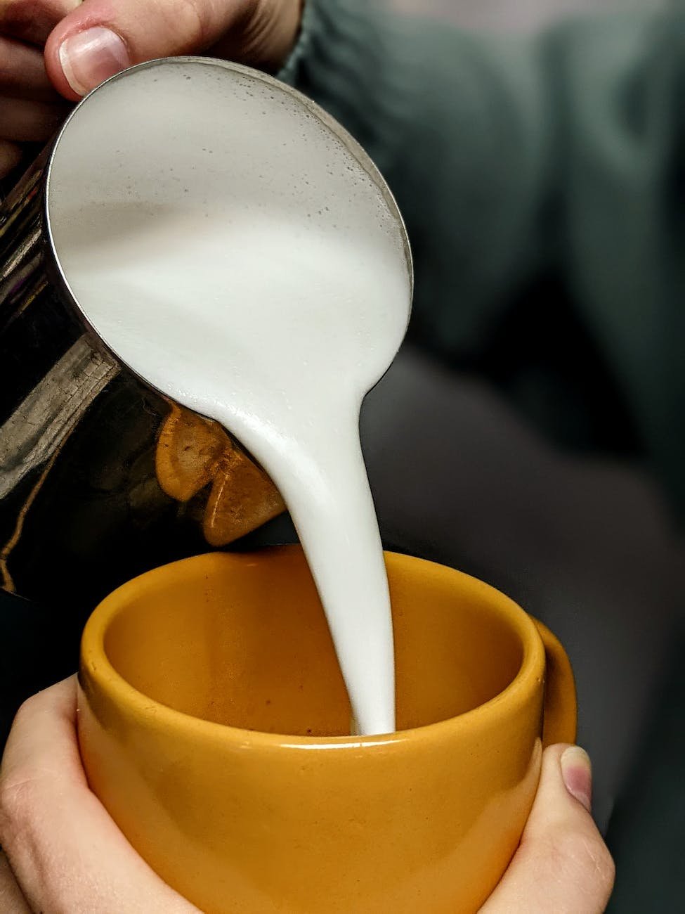 close up of person pouring frothed milk into a mug